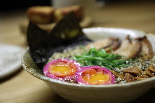 Bowl of ramen noodles with eggs wakame salad and sesame seeds on table closeup