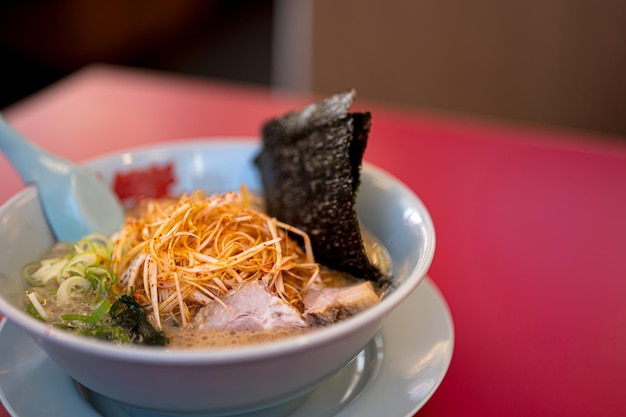 A bowl of ramen with a red tablecloth on the table