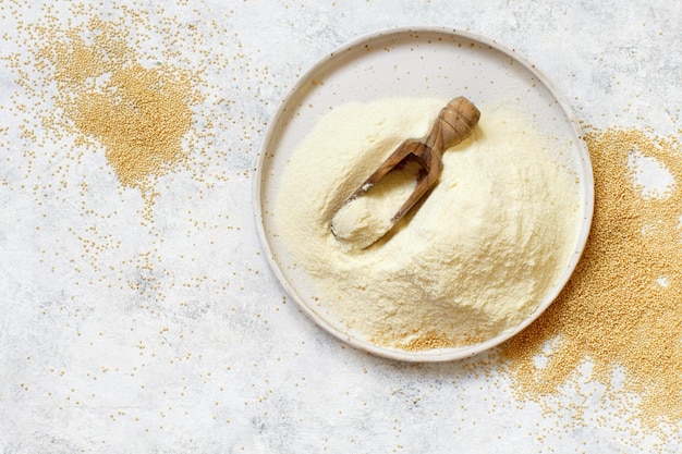 Photo bowl of raw amaranth flour with a spoon of amaranth seeds top view