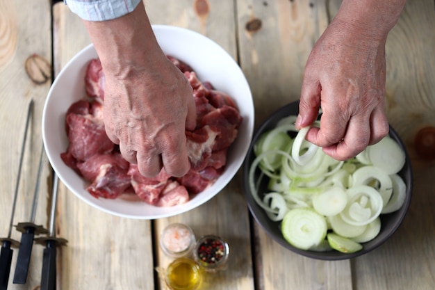 A bowl of raw meat and a bowl of onions.