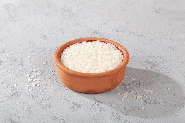 Photo a bowl of raw rice on concrete ground