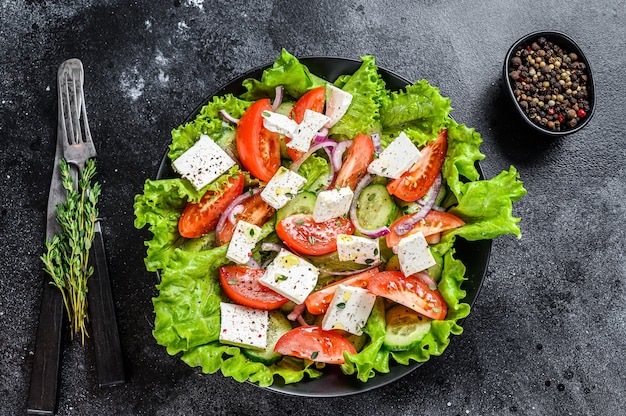 Bowl of ready-to-eat Greek salad. Black background. Top view.