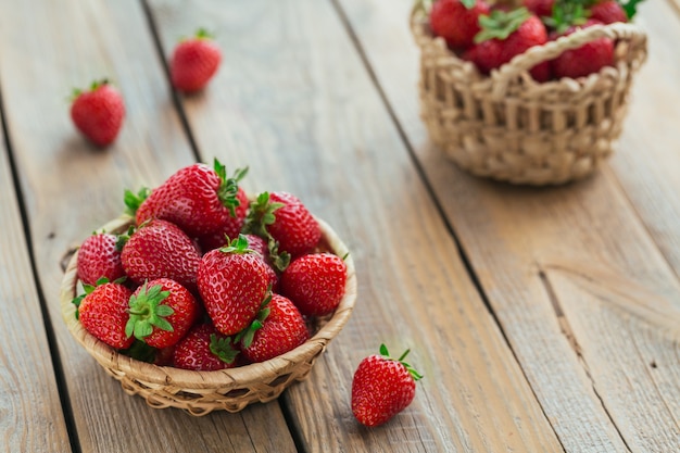 A bowl of red juicy strawberries on rustic wooden table. Healthy and diet snack food concept.