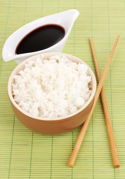 Bowl of rice and chopsticks on bamboo mat