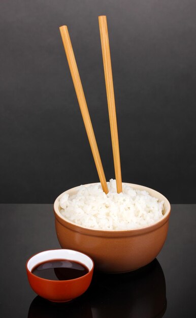 Photo bowl of rice and chopsticks on grey background