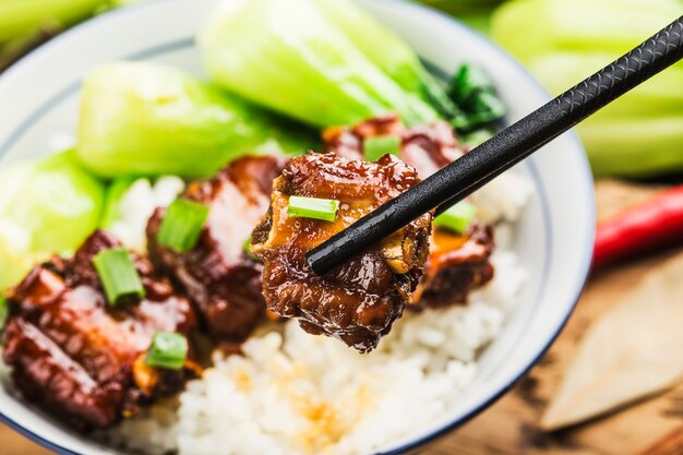 A bowl of rice with ribs in brown sauce