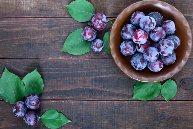 A bowl of ripe blue plums cherry plum on dark wooden table 