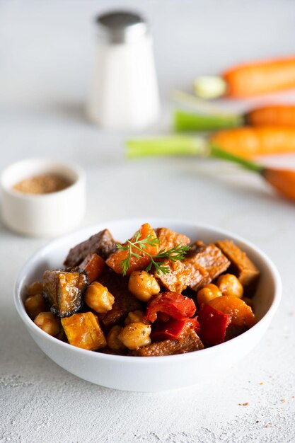 Photo a bowl of roasted vegetables with a spoonful of chickpeas.