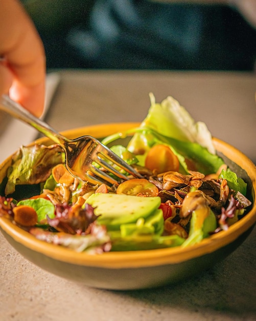 A bowl of salad with a fork in it