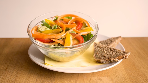 A bowl of salad with a slice of bread on the side.