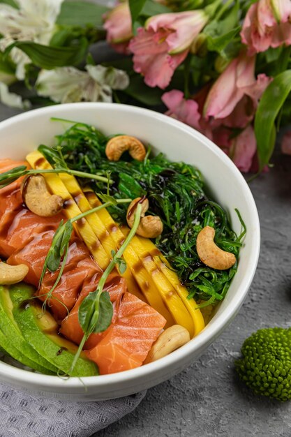 A bowl of salmon, avocado, and spinach salad