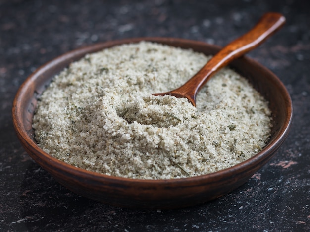 A bowl of salt and spoon of dark wood on a wooden rustic table.