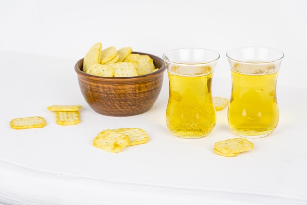 A bowl of salty crackers and two glasses of beer