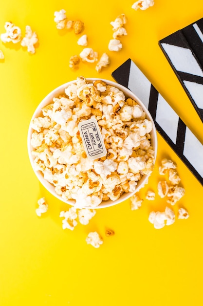 Bowl of salty popcorns on a yellow background. Cinema snack concept. Flat lay top view