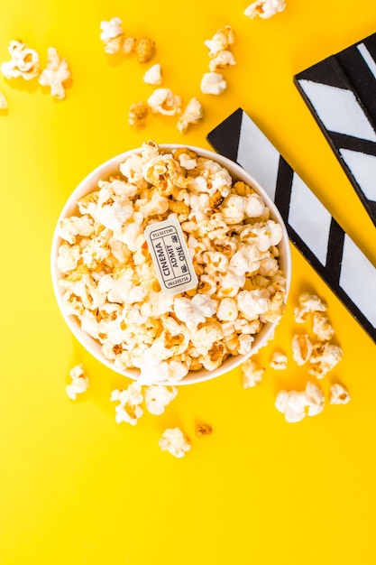 Bowl of salty popcorns on a yellow background. cinema snack concept. flat lay top view