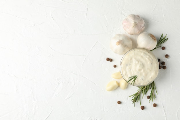 Foto ciotola di salsa, bulbi d'aglio, fette, spezie, rosmarino su bianco, vista dall'alto. spazio per il testo
