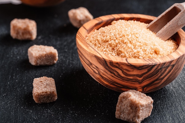 Bowl and scoop with sand and lump brown sugar on wooden
background brown sugar cube make unhealthy nutrition obesity
diabetes dental care and much more