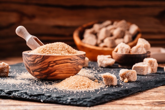 Bowl and scoop with sand and lump brown sugar on wooden
background brown sugar cube make unhealthy nutrition obesity
diabetes dental care and much more