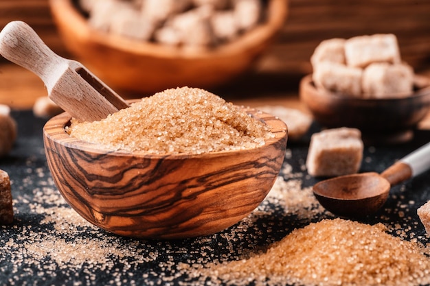 Bowl and scoop with sand and lump brown sugar on wooden background brown sugar cube Make unhealthy nutrition obesity diabetes dental care and much more