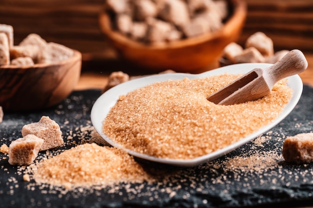 Bowl and scoop with sand and lump brown sugar on wooden
background brown sugar cube make unhealthy nutrition obesity
diabetes dental care and much more