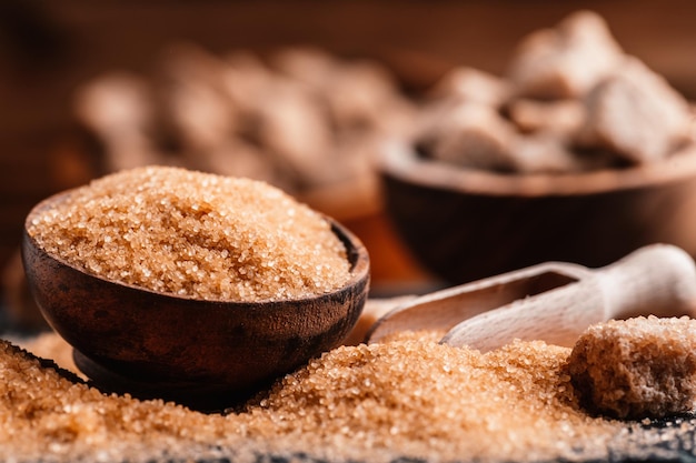 Bowl and scoop with sand and lump brown sugar on wooden background brown sugar cube Make unhealthy nutrition obesity diabetes dental care and much more