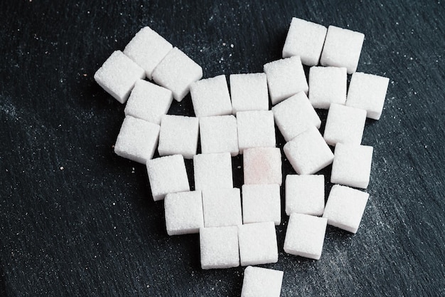 Foto ciotola e misurino con sabbia bianca e zolletta di zucchero bianco su sfondo di legno zolletta di zucchero fare alimentazione malsana obesità diabete cure dentistiche e molto altro