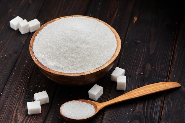 Photo bowl and scoop with white sand and thick sugar on wooden background