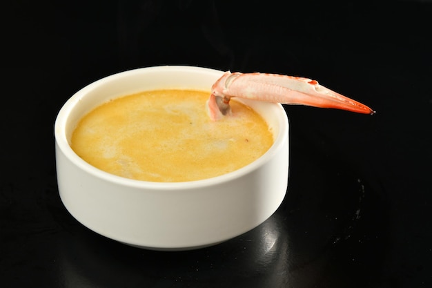 A bowl of shrimp soup with a piece of meat on top