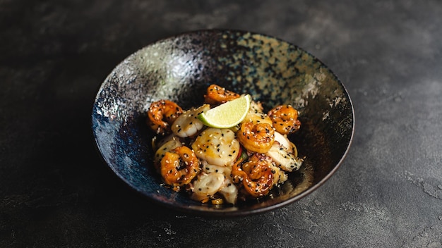 A bowl of shrimp with a lime wedge on the side