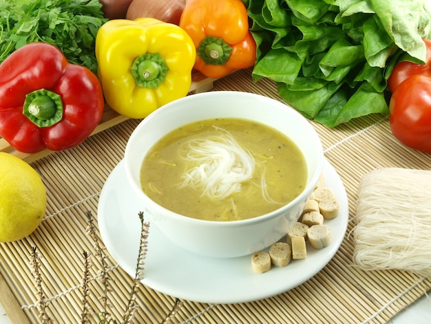 A bowl of soup with a bunch of vegetables on the table