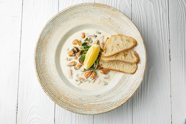 A bowl of soup with toasts and lemons on top