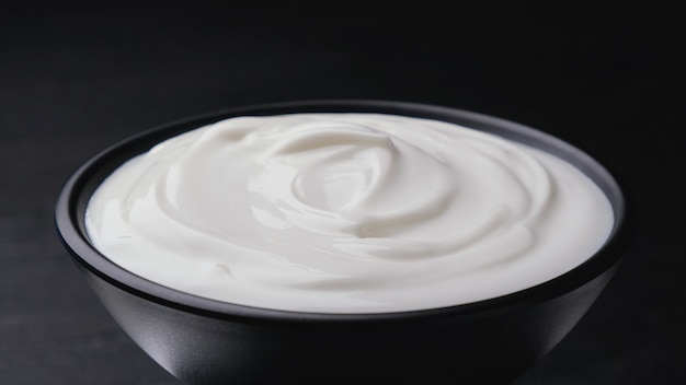 Bowl of sour cream on black, greek yogurt