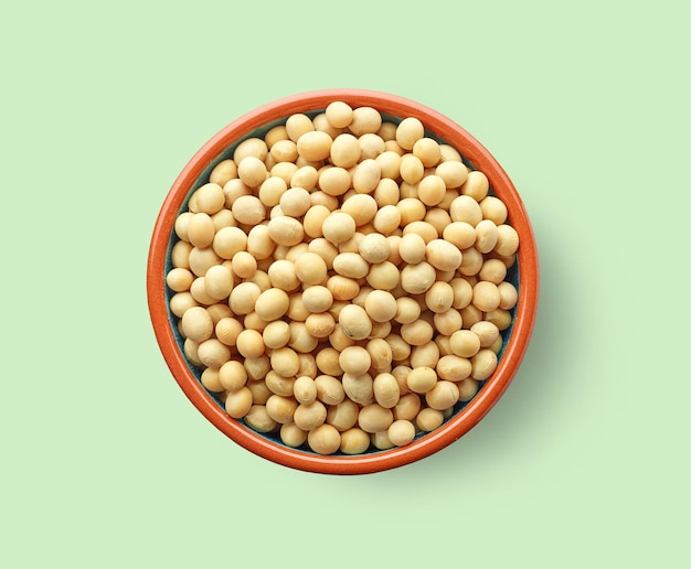 Bowl of soy beans on light green background, top view