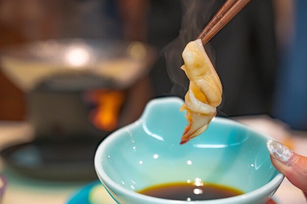 A bowl of soy sauce with a plate of food with a plate of food in the background.