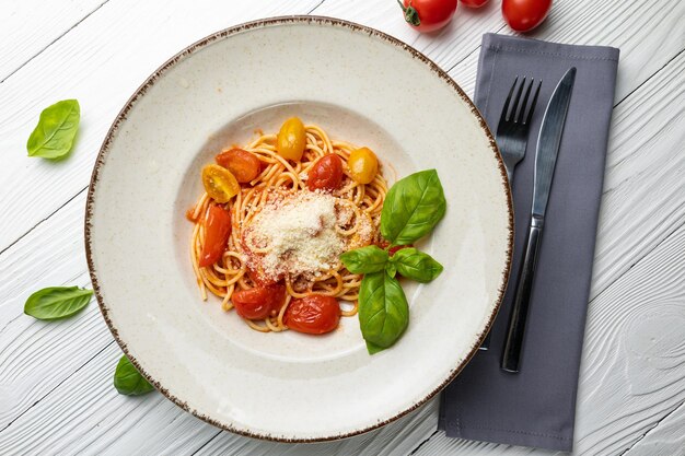 A bowl of spaghetti with tomato sauce and basil leaves on a table.