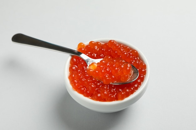 Photo bowl and spoon with caviar on gray background