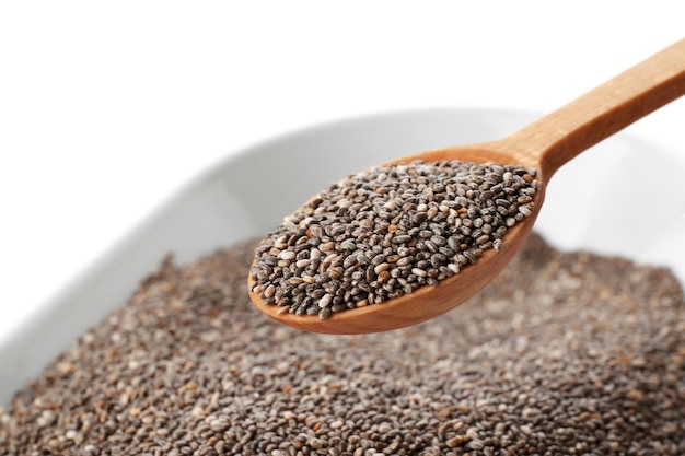 Bowl and spoon with chia seeds on white background closeup