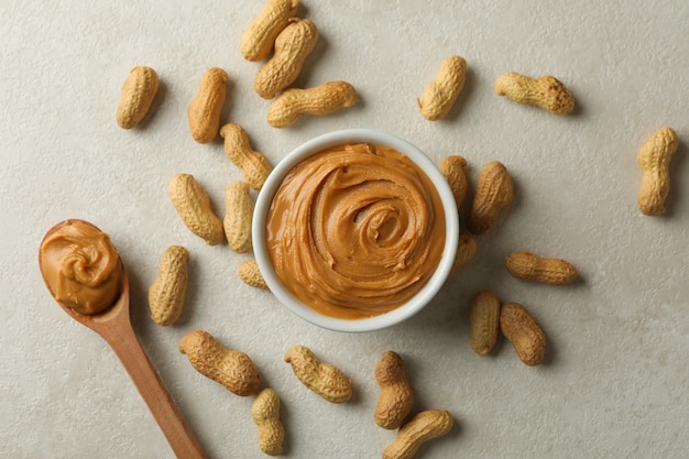 Photo bowl and spoon with peanut butter, and peanut on gray background