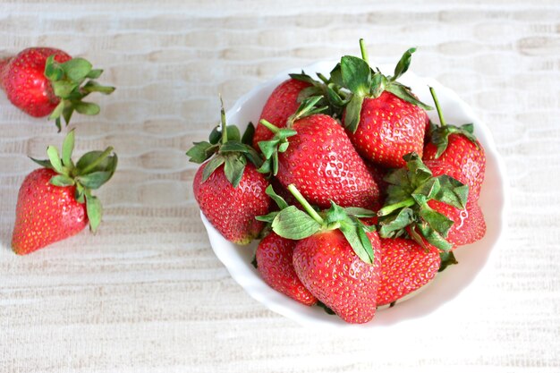 A bowl of strawberries on a table isolated on beige background closeup