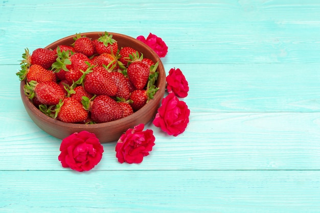 Bowl of strawberry harvest on wooden table 