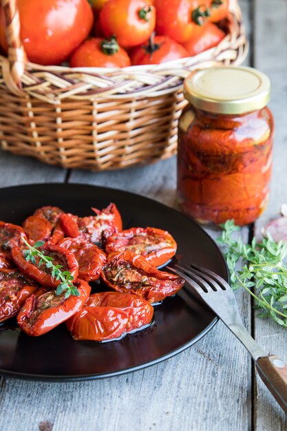 Ciotola di pomodori seccati al sole su fondo di legno. pomodori essiccati al sole con olio d'oliva ed erbe aromatiche