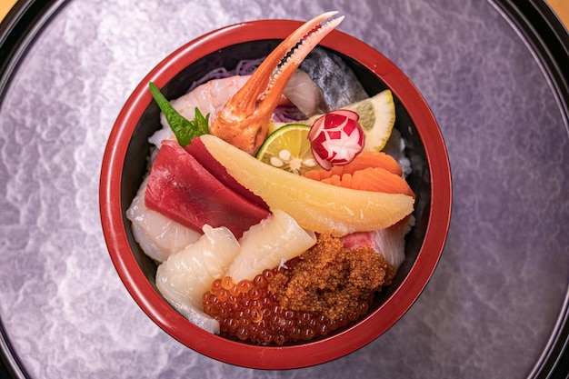 A bowl of sushi with a variety of ingredients including sushi, shrimp, and lemon