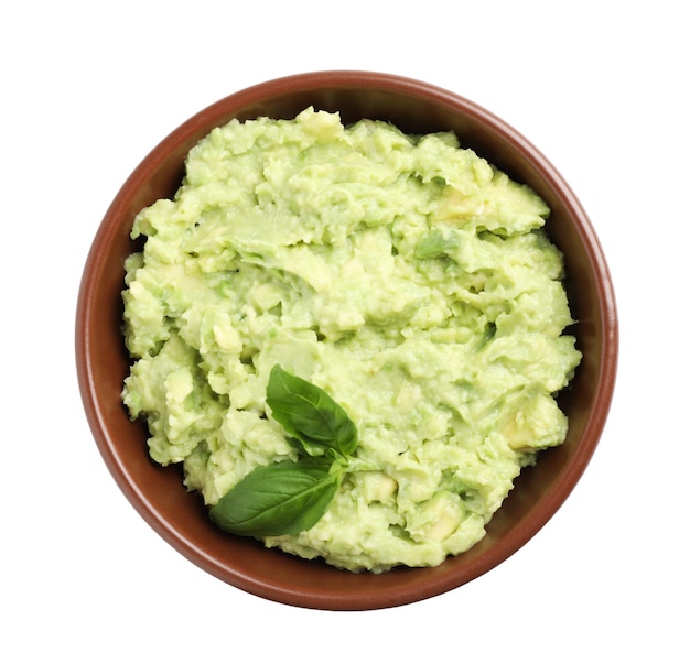 Bowl of tasty avocado sauce with basil on white background top view