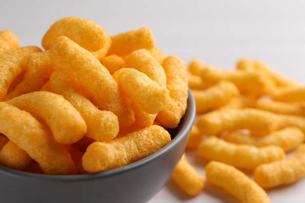Photo bowl of tasty cheesy corn puffs closeup space for text