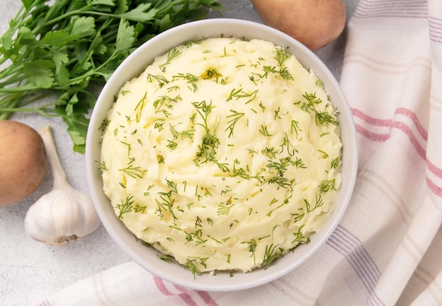 Bowl of tasty mashed potato parsley and pepper on grey marble table