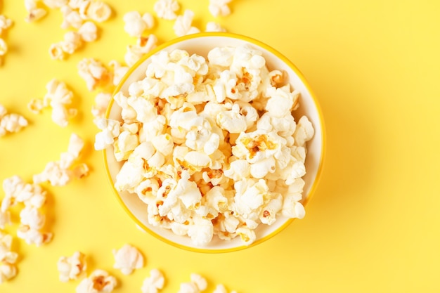 Bowl of tasty popcorn on color background