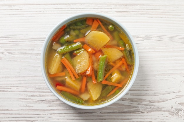 Bowl of tasty turnip soup on white wooden table top view