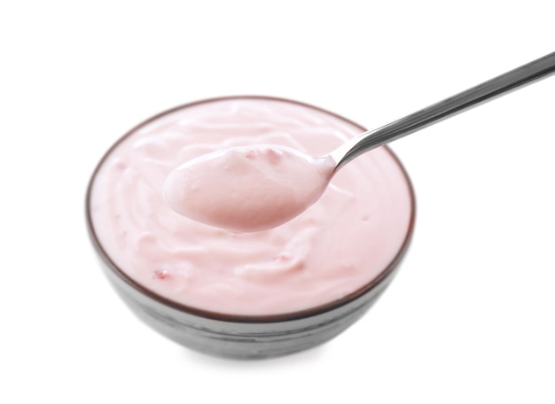 Bowl of tasty yogurt and spoon on white background