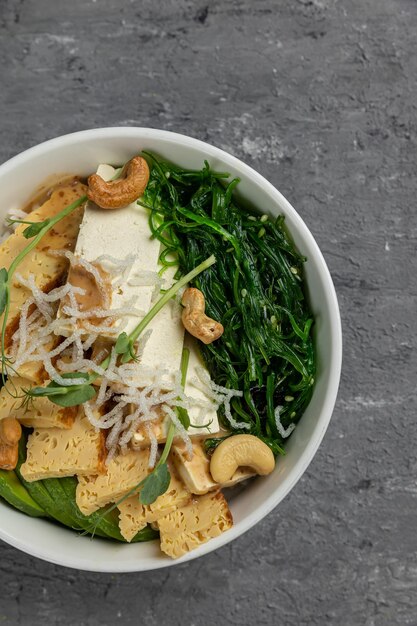 A bowl of tofu with greens and nuts