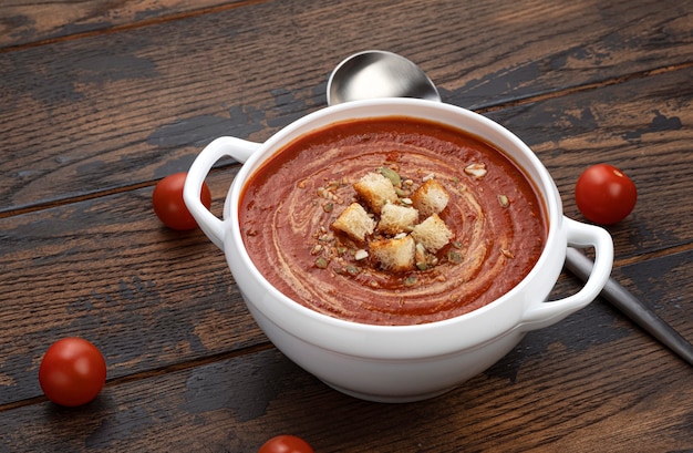 Bowl of tomato soup on wooden background